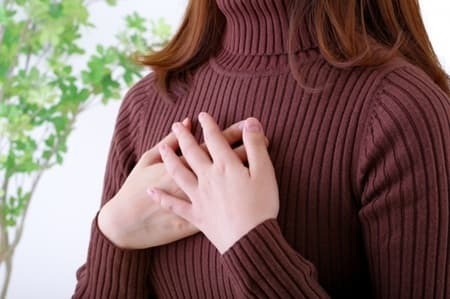 心臓を抑える不安そうな女性
